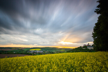 Landscape at sunrise. Beautiful morning landscape with fresh yellow rapeseed fields in spring. Small castle in the yellow fields on a hill. Historic Ronneburg Castle, Ronneburg, Hesse, Germany