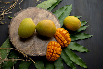 Mango tropical fruit with slice and half cut on green leaf background