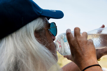 Senior thirsty man feel thirst and drinking water from sport bottle for healthy hydration balance....