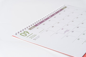 A desk calendar of 2024, September page lying on white background, side view and selective focus shot. Concept of season, time and event in a year. 