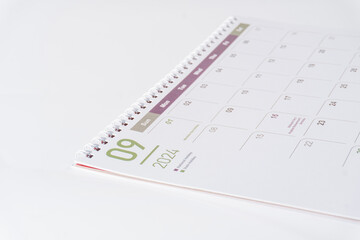 A desk calendar of 2024, September page lying on white background, side view and selective focus shot. Concept of season, time and event in a year. 