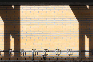bike rack at yellow brick wall and shadows of posts right and left