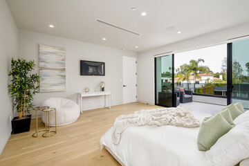 the bedroom features hardwood floors and large windows, including sliding doors