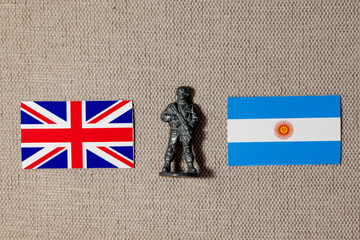 A soldier figurine on the background of the flags of Great Britain and Argentina