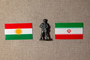 A soldier figurine on the background of the flags of Iran and Kurdistan