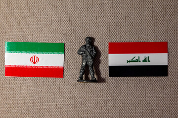 A soldier figurine on the background of the flags of Iran and Iraq