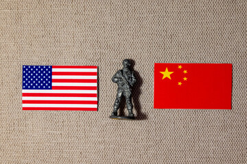 A soldier figurine on the background of the flags of the USA and China