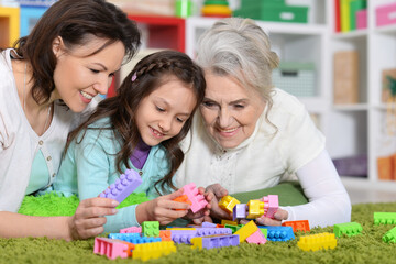 Portrait of cute girl playing with mom and grandma in cubes 