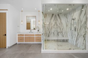 the bathroom features large marble shower and wood cabinetry, and matching floor and walls