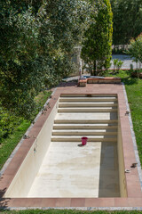 A concrete swimming pool has been emptied for maintenance and is waiting to be filled with clean water