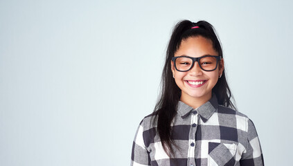 Portrait, girl and kid with glasses, student and confident geek on blue studio background. Face, happy person and model with smile, joy or eyewear for clear vision, looking and mockup space with nerd