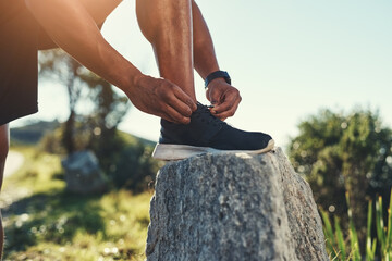 Runner, legs and tie shoelaces on rock, outdoors and prepare for cardio and marathon training. Man, stone and shoe for exercise or sports in nature, getting ready and foot for workout or athlete