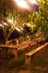Prepared table for a rustic outdoor dinner at night with lamps