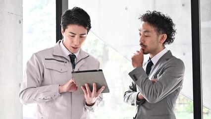 タブレットを見て打ち合わせをする作業服の人と社長や管理職のビジネスマン　itやdxの動画