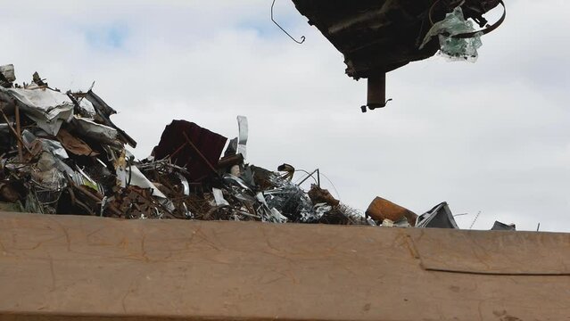 Crane loading stamped metal. A crane lifts an old salvaged car body. Disposal of an old unusable car.