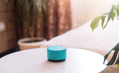 Blue wireless smart speaker on white table in room.