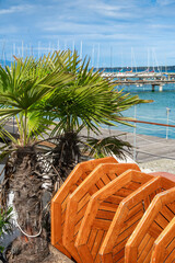 Folded and cleaned wooden tables of a restaurant on the shores of Lake Geneva, small palm trees. End of bathing season.