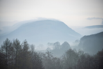 Stunning layered landscape image of misty Spring morning in Lake District looking towards distant misty peaks - 783776305