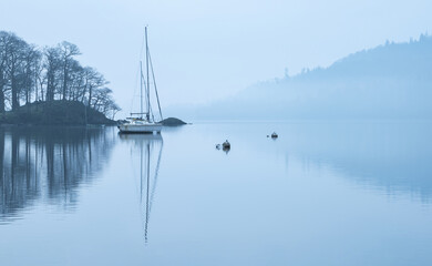 Stunning peaceful landscape image of misty Spring morning over Windermere in Lake District and distant misty peaks - 783776396