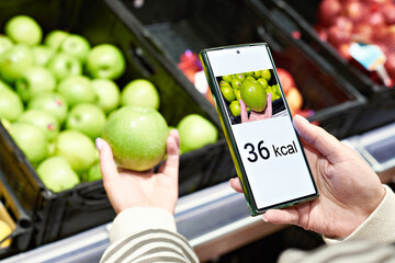 Checking calories on a apple fruit in store with smartphone