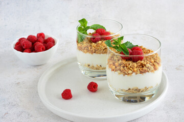 a glass of oatmeal with raspberries and yogurt isolated on white tray 