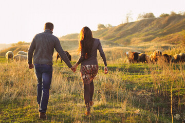 Couple holding hand in hand romantic walk on the autumnal meadow
