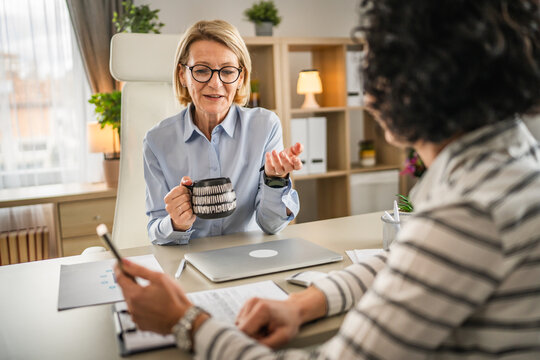 Two Mature Woman Have Coffee Break At Office