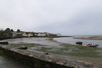 A grey spring view across the beach towards some coastal cottages at Parrog, Newport,...