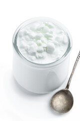 Granular cottage cheese with cream in a glass jar isolated on white
