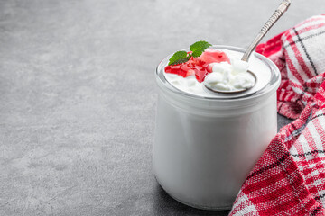 Granular cottage cheese with cream and berry jam on gray background