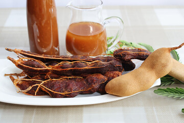 Ripe, peeled tamarind on the next plate is freshly squeezed juice in pitchers and bottles. Place...