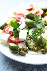 Healthy Salad with Feta Cheese, Green Olives, Baby Spinach, Cucumber, Cherry Tomatoes and Capers. Bright background. Close up.	