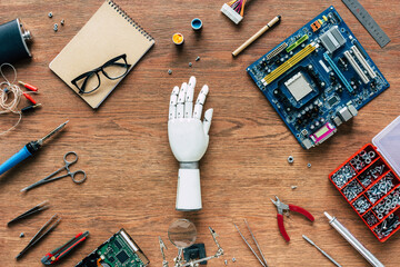 top view of prosthetic arm on wooden table with tools, spectacles and textbook - Powered by Adobe
