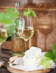 Glasses of white wine, bottle and cheese