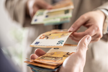 Businesswoman's hands exchanging euro banknotes, closeup shot - 783799993