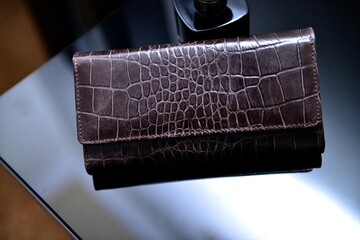 A chocolate brown color ladies' purse made with premium quality leather of crocodile skin texture,...