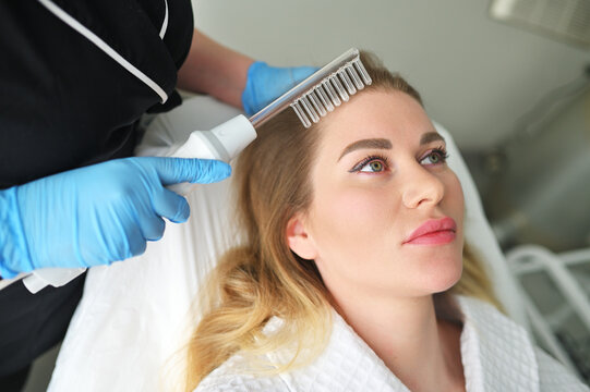 dermatologist trichologist performs the procedure with a darsonval device to improve the condition and quality of the patient's hair.