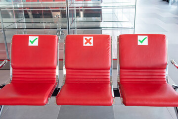 Red airport chairs arranged for social distancing with caution signs
