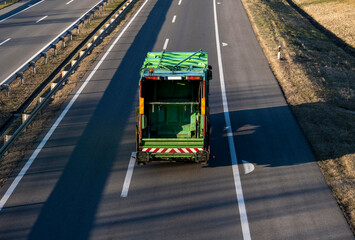 Green Truck for transportation of municipal waste (garbage truck) moves on an empty highway. Urban...