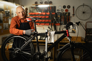 Elderly man bicycle mechanic is repairing a bike in the authentic workshop