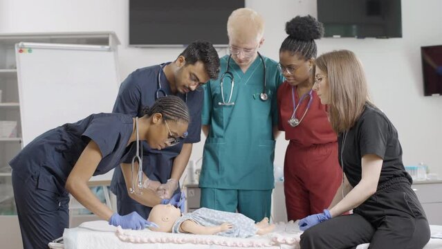 Group of doctors examining baby dummy in medical clinic