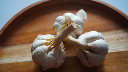 Isolated garlic or Allium sativum on a wooden tray. Selective focus                              - obrazy, fototapety, plakaty