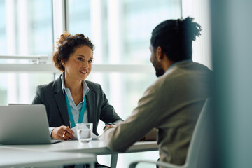 Smiling businesswoman talking job candidate during  interview in office.