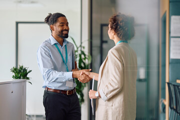 Happy black job candidate shaking hands with female CEO in office.