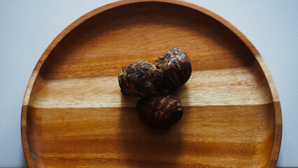 Close up isolated flat lay taro tuber or Colocasia esculenta on a wooden tray.
