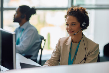 Smiling customer service representative working on computer in office.
