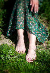 Barefoot woman in a green dress sitting on the grass