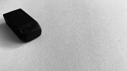 Black and white photo of paper and eraser on table
