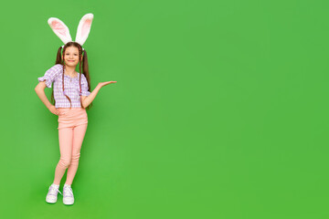 A little girl with rabbit ears on her head points to your ad. The child is standing in full height...