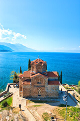 Ohrid, North Macedonia - April 13, 2024: Church of Saint John the Theologian overlooking Lake Ohrid. The mountain range and peninsula in distance. The clear mesmerizing waters of lake Ohrid. 